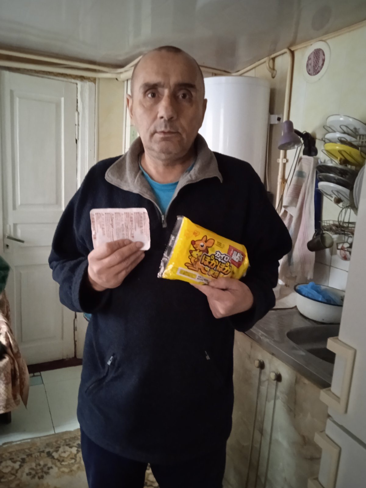 ホッカイロを胸の前に持って立っている男性